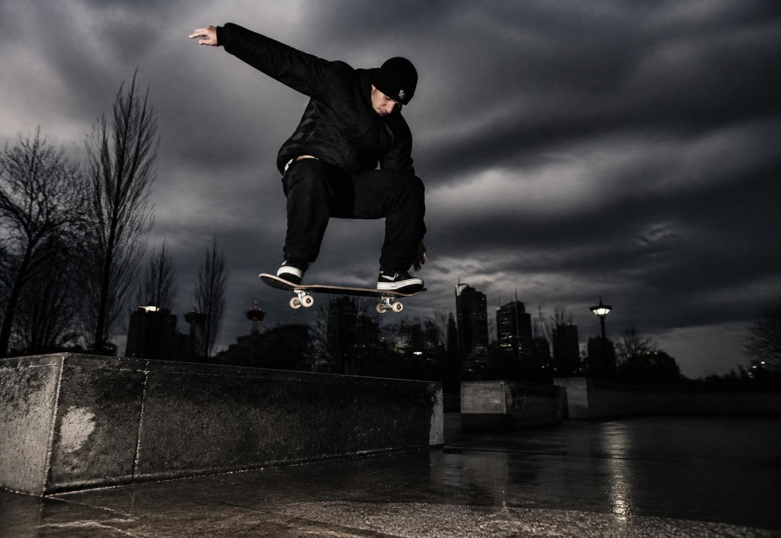 Skateboarder ollieing a concrete stair set at night under harsh flash